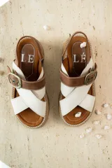 Sandalias bajas color marrón de cuero gamuzado, con tiras cruzadas y hebilla metálica.