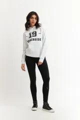 Buzo hoodie blanco con estampado de letras y número 19 en negro.