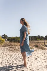 Vestido celeste de lino con mangas cortas y falda midi con volados de seda.