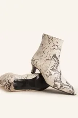 Bota corta de cuero vacuno con estampado animal print serpiente en tonos blanco y negro, con puntera fina y cierre trasero. Tiene taco chupete y suela de cuero.