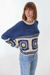 Sweater azul con cuello redondo y diseño de cuadrados de crochet en la parte inferior.