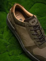 Zapatillas urbanas de cuero color verde oliva con detalles en marrón y negro. Presentan el logo de Star Wars en el talón y el rostro de Yoda grabado en el lateral.