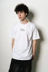 Remera blanca de algodón, corte regular fit, con un pequeño estampado ovalado en el pecho y un gran estampado de firma estilizada en la espalda.