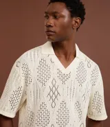 Camisa polo de mangas cortas color crema, confeccionada en tejido de punto calado con cuello inglés.