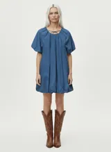 Vestido corto azul denim de corte suelto, con cuello redondo, mangas globo y lazo ajustable en el escote.