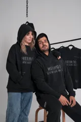 Canguro negro unisex con capucha y estampa frontal con el logo de la marca Hermod y la frase "Is the new black".