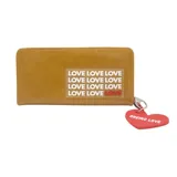 Billetera color camel con cierre perimetral y llavero de corazón rojo con la inscripción "Oreiro Love". Estampado frontal con la palabra "Love" repetida.