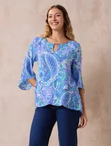 Blusa de gasa estampada con motivos paisley en tonos azules, marca Ruby Rd. Tiene cuello redondo con escote en V y aplique metálico. Presenta una sobre capa delantera y terminación asimétrica. Las mangas son 3/4 y amplias.