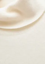 Jersey de cashmere color crema, con cuello alto y mangas cortas.
