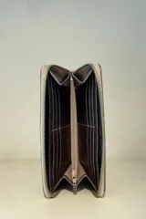 Billetera de charol color rojo con cierre perimetral y logo metálico plateado en el frente.