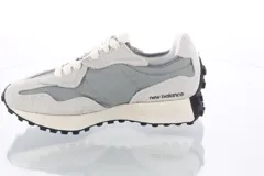 Championes urbanos New Balance modelo 327, color gris con detalles en azul, confeccionados en gamuza y nylon, con logo "N" característico en los laterales y entresuela de goma.