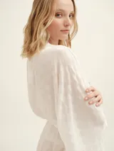 Bata color blanco con estampado de lunares, mangas largas y lazo para ajustar en la cintura.