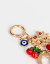 Llavero metálico dorado con dije de mosquetón y charms colgantes: ojo turco, trébol de cuatro hojas con la palabra "LUCK", cerezas, herradura, corazón rojo y mariquita celeste con lunares negros.