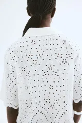 Camisa blanca de algodón con broderie, corte holgado, cuello abierto, mangas anchas al codo y ribete festoneado en mangas y bajo.