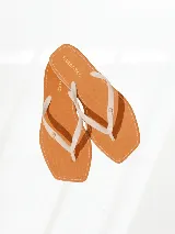 Chinelas color naranja con tiras blancas y logo de la marca en dorado.