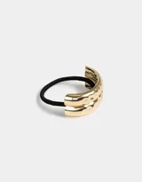 Gomita de pelo elástica negra con aplique metálico dorado con textura irregular.