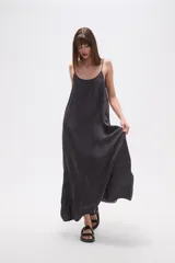 Vestido largo de lyocell, color gris oscuro con efecto lavado, de corte holgado y tirantes finos. Presenta costuras diagonales que crean paneles en la tela.
