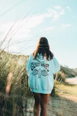 Hoodie color natural con estampado en la espalda con la frase "Glassy Waves" y una tabla de surf con alas.