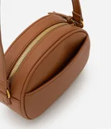 Bolso camera bag pequeño de poliuretano color negro, con forma redondeada, correa ajustable, bolsillo delantero y cierre superior.