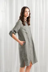 Túnica blanca de lino, corte holgado, con cuello mao, cierre frontal con botones y mangas largas con trabillas para enrollar.