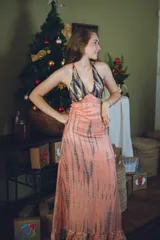 Vestido largo color marrón cobrizo con escote en V, cut outs laterales bajo el busto y breteles finos que se cruzan y atan en la espalda. Presenta un top con estampado abstracto en tonos marrones y dorados.