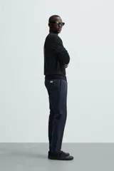 Pantalón chino color beige, corte skinny fit, confeccionado en tejido con mezcla de algodón y elasticidad. Cuenta con bolsillos frontales y traseros. Cierre frontal con cremallera y botón.