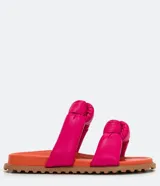 Sandalias planas con tiras puffa con nudo, color fucsia y suela naranja.