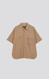 Camisa beige de manga corta con doble bolsillo ojal en delantero, uno de ellos con solapa. Silueta oversize.