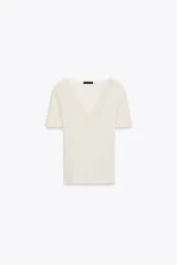Camiseta color crema de tejido de punto rib, corte slim fit, escote en pico con detalle de encaje y mangas cortas.