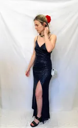 Vestido largo de fiesta azul marino con lentejuelas, escote en V y breteles finos. Presenta tajo lateral alto.