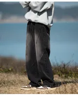 Jean de mezclilla color negro lavado, corte ancho y holgado, caracterizado por costuras diagonales pronunciadas en la parte delantera de las piernas que crean un efecto de paneles o cortes asimétricos.