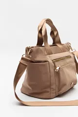 Cartera negra de nylon con diseño compacto y funcional. Cuenta con asas cortas y correa regulable desmontable para llevar al hombro o cruzada, además de múltiples bolsillos con cierre y detalles dorados.