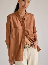 Camisa color marrón de lino y viscosa, de corte clásico, con cuello camisero, cierre frontal con botones, mangas largas con puños abotonados y dos bolsillos de parche en el pecho.