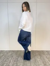 Camisa blanca de algodón con cuello clásico, corte recto y mangas largas con puños abotonados. Cierre frontal con botones.