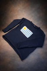 Sweater de punto color azul marino, con cuello redondo y manga larga. Presenta un diseño tejido de la bandera de Uruguay en el frente.