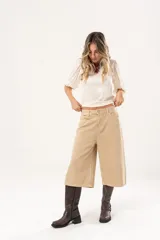 Bermuda de jean color beige, tiro medio, con bolsillos delanteros y traseros.