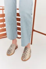 Zapatillas de charol negro con decoración de perlas, diseño abierto en la parte trasera.