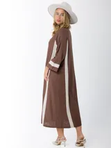 Vestido camisero marrón con rayas verticales color crema, de corte recto y largo midi. Presenta cuello en V, cierre frontal con botones y bordados en el ruedo.