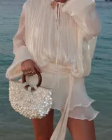 Bolso de mano con forma de media luna cubierto de perlas sintéticas. Tiene asas circulares de madera y detalles de cuentas en la unión con el cuerpo del bolso.