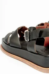 Sandalias negras de cuero con plataforma y tiras cruzadas en el empeine y tira con hebilla alrededor del tobillo.