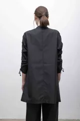 Vestido negro de microfibra con corte recto, cuello alto, cierre frontal y mangas largas con sistema de frunce ajustable.