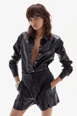 Camisa negra de lino metalizado con cuello camisero clásico, mangas largas y ruedo curvo más largo atrás.