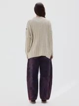 Buzo tejido color blanco, con cuello subido tipo polera, diseño oversized y largo con pequeños cortes laterales.