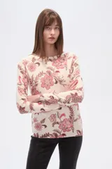 Sweater de tejido de punto, color crema, con estampado floral en tonos rosados y marrones. Presenta cuello redondo y mangas largas.