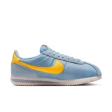 Championes Nike Cortez celestes con detalles en amarillo y suela blanca.