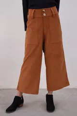 Pantalón marrón de pana con corte cropped, tiro alto, bolsillos frontales y cierre con doble botón.