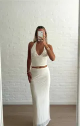 Conjunto color beige compuesto por un top halter con apliques circulares y una falda midi ajustada.