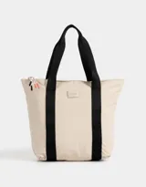 Cartera shopper color beige de tela deportiva con doble asa de hombro, cierre superior con puller de cordón y goma, y tag de goma.