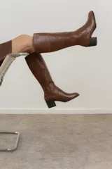 Bota de cuero color marrón, de caña alta y taco cuadrado.