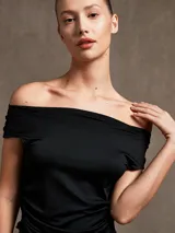 Top negro con escote off-shoulder y corte irregular en el ruedo.